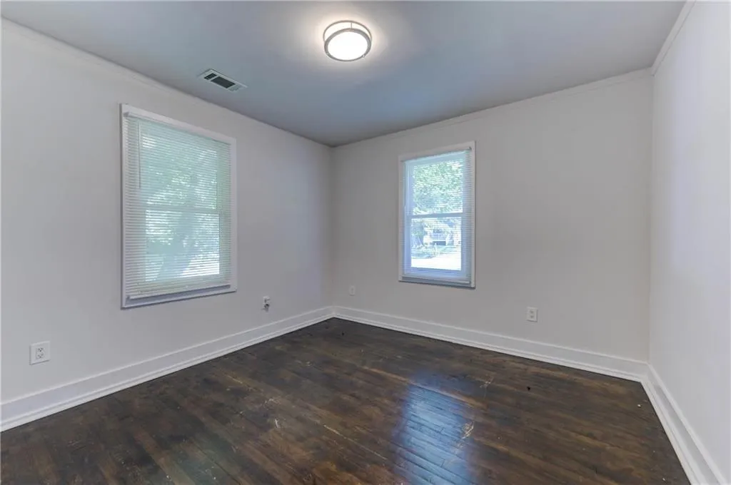 Empty room with dark wood finished floors and crown molding