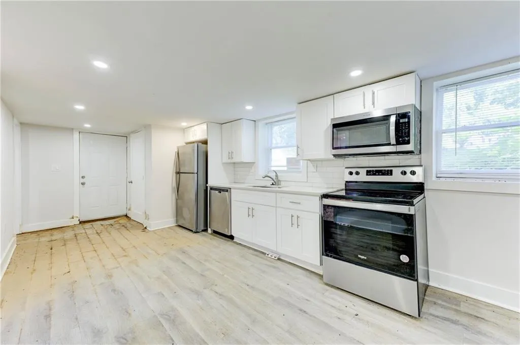Kitchen featuring appliances with stainless steel finishes, light wood finished floors, white cabinetry, light countertops, and recessed lighting