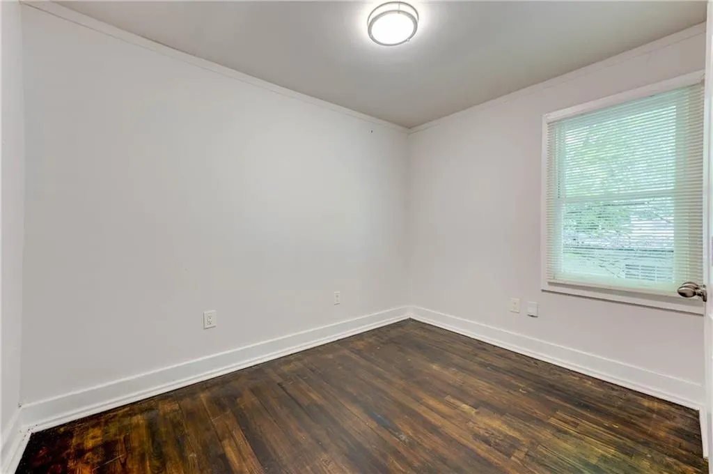 Unfurnished room with ornamental molding and dark wood-type flooring