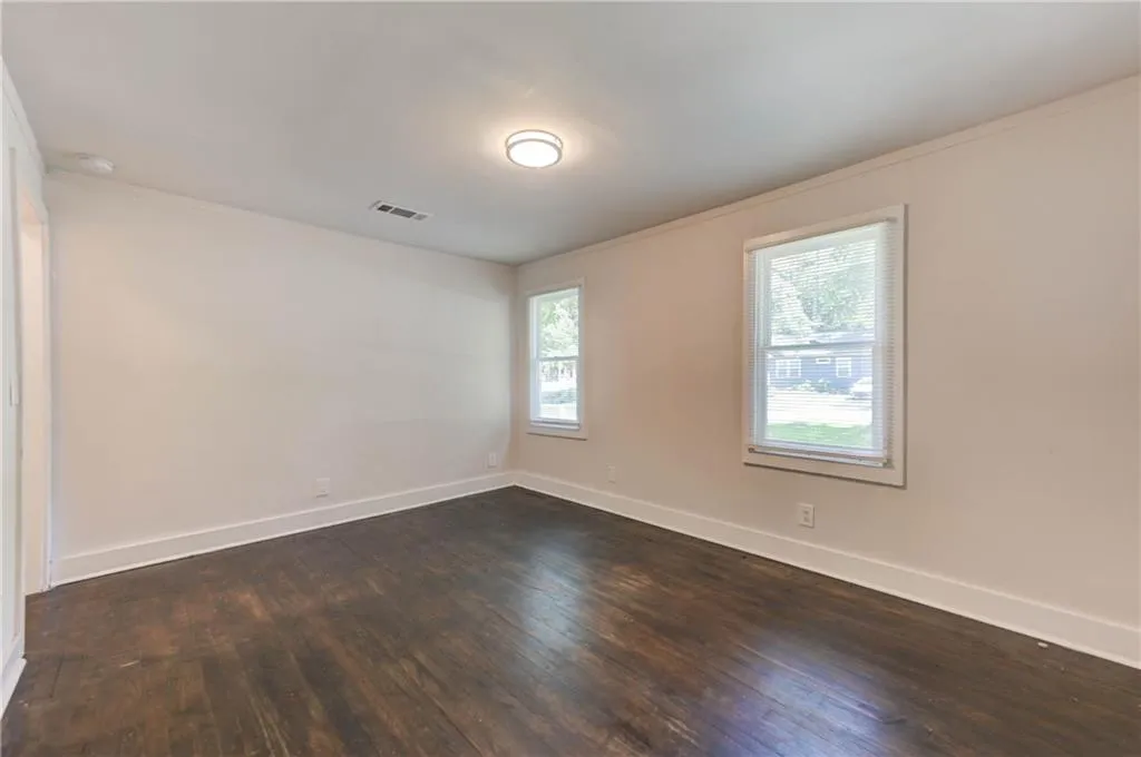 Unfurnished room featuring dark wood-style floors, a smoke detector, and crown molding