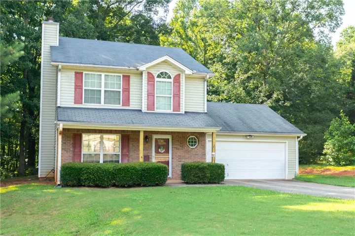 Two-story residence featuring a brick and siding facade, a covered front porch, and a two-car garage