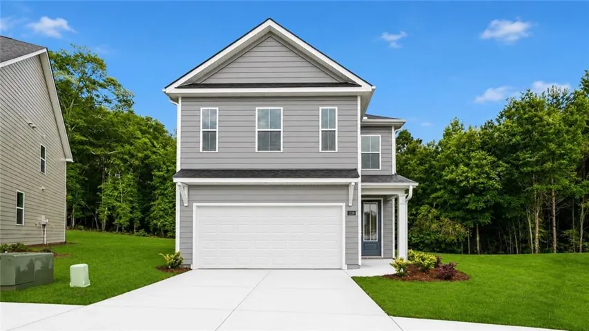 Two-story residence featuring light gray siding, white trim, and a prominent front-facing garage