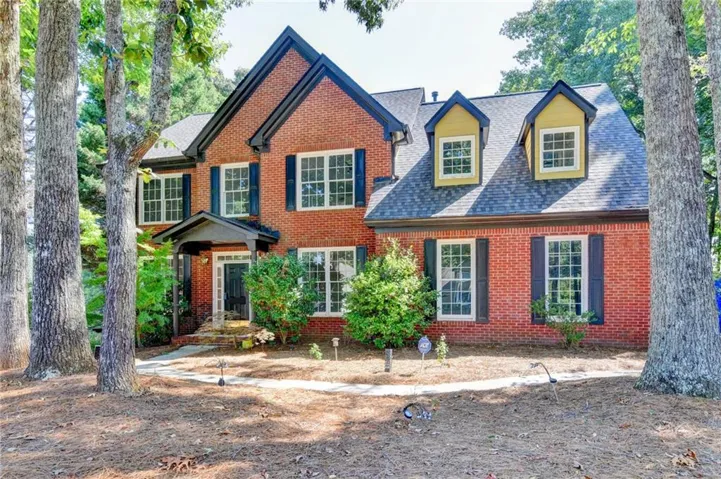 Brick facade residence with a dark shingle roof and contrasting dark shutters