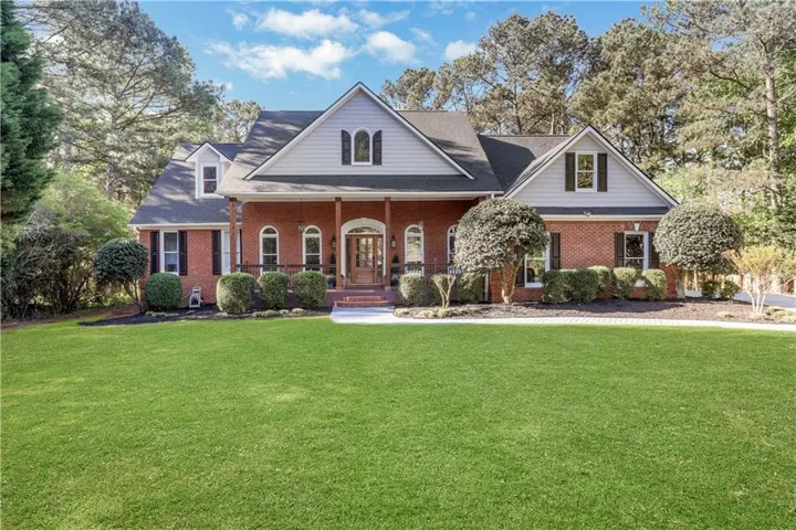 Brick Colonial residence showcasing a symmetrical facade with multiple gabled rooflines, arched entryway with sidelights, and paired chimneys