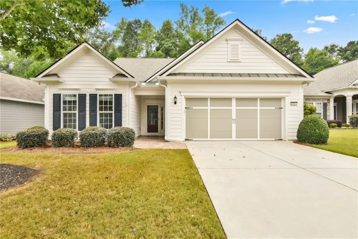 White siding exterior with dark shutters, gabled rooflines, and a two-car garage
