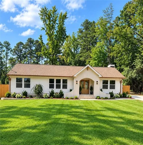Inviting facade with a stucco entryway, double wooden front doors, and white siding