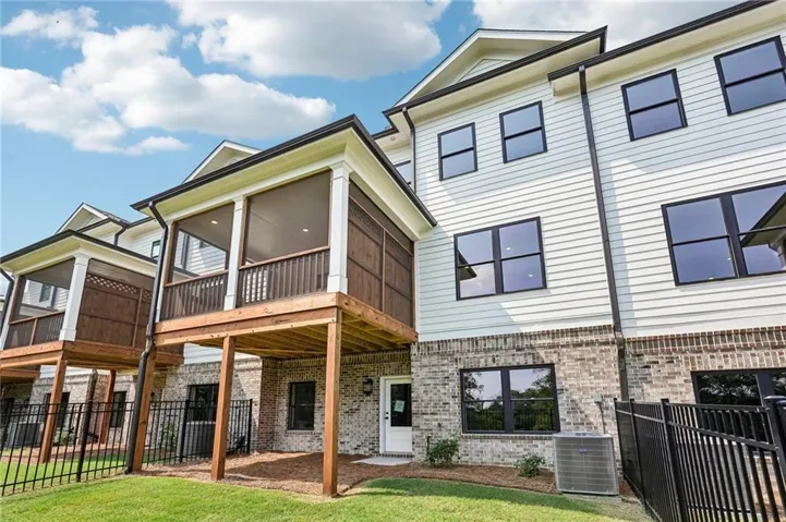 Welcome Home!! Screened in Deck and fenced in yard!!! Rear exterior featuring a screened porch, white horizontal siding, light-colored brick foundation, black-framed windows, and a black wrought-iron fence