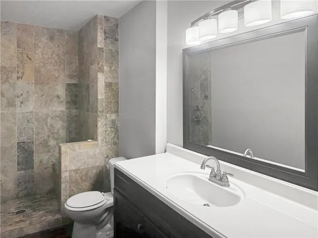 Tile shower with built-in bench, single vanity with integrated sink, framed mirror, and a five-light fixture