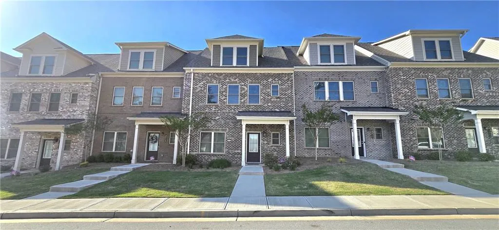 Multi unit property featuring a front lawn and brick siding