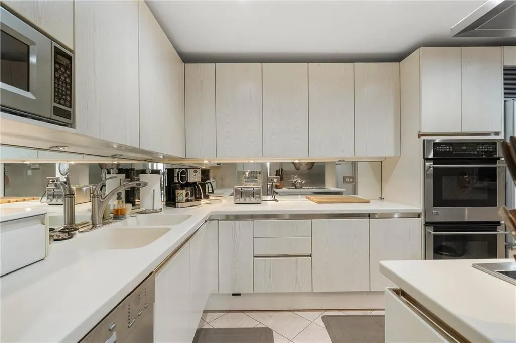Kitchen featuring light tile patterned floors, a toaster, stainless steel appliances, light countertops, and a sink