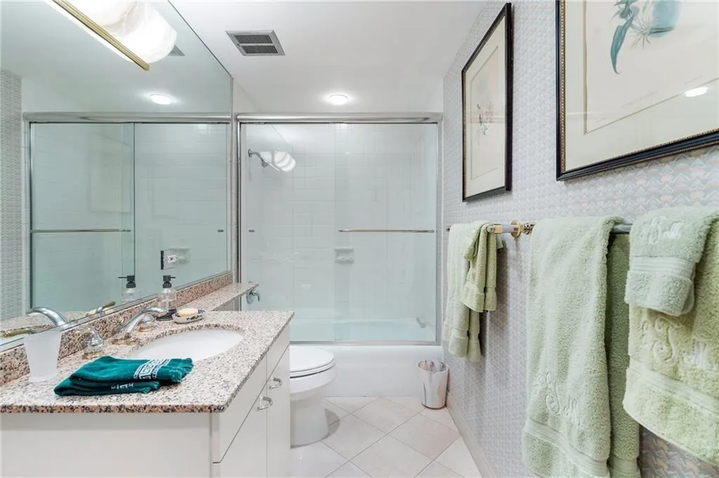 Full bathroom featuring shower / bath combination with glass door, visible vents, toilet, vanity, and tile patterned flooring