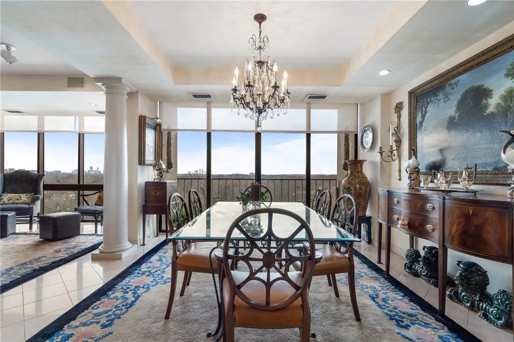 Dining space featuring a tray ceiling, ornate columns, and tile patterned floors