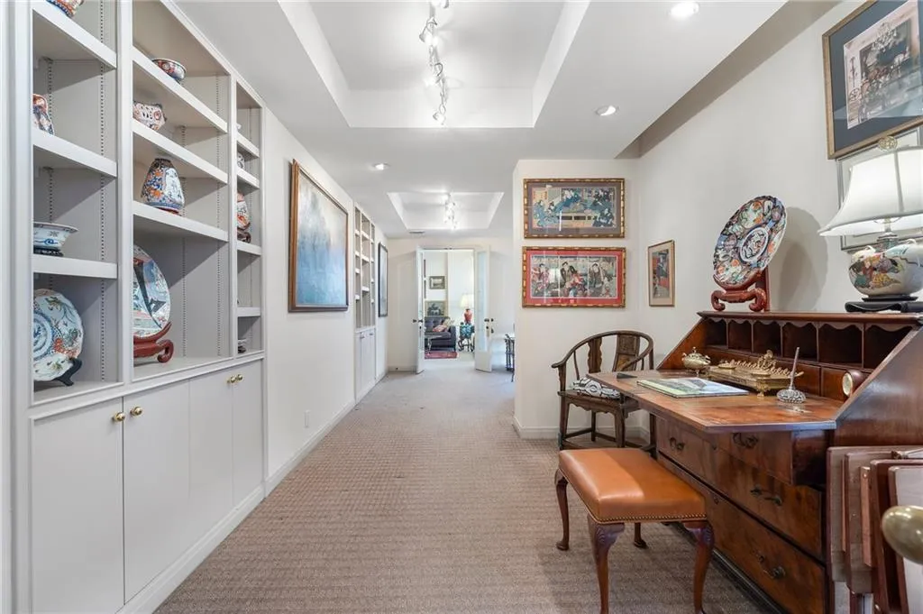 Hallway with baseboards, a tray ceiling, rail lighting, and light colored carpet