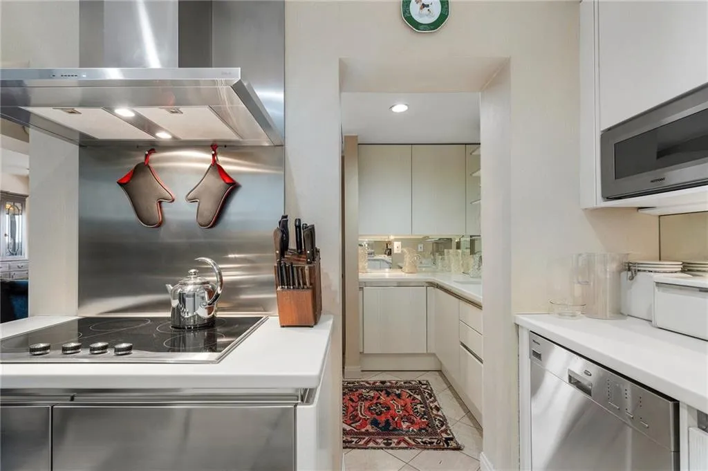 Kitchen featuring stainless steel appliances, wall chimney range hood, backsplash, and light countertops