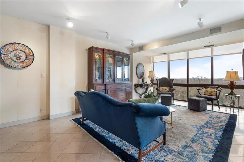Living room with a wall of windows, light tile patterned flooring, visible vents, and baseboards