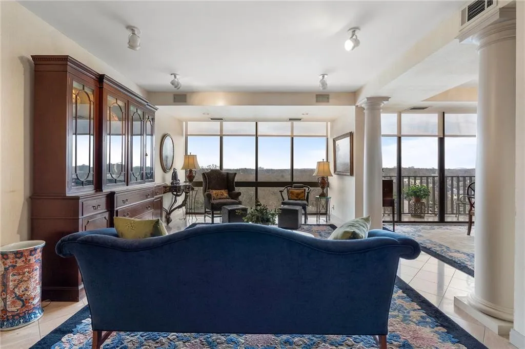Living area featuring floor to ceiling windows, light tile patterned flooring, plenty of natural light, and ornate columns