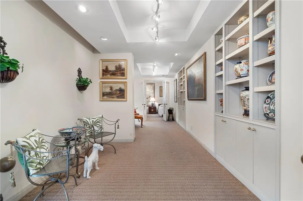 Hallway with recessed lighting, light carpet, baseboards, a tray ceiling, and track lighting