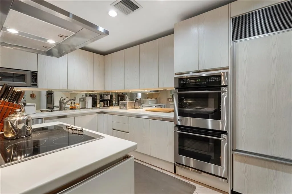 Kitchen featuring a sink, exhaust hood, visible vents, light countertops, and appliances with stainless steel finishes