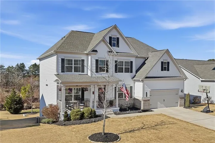 Elegant two-story Colonial home featuring a crisp white exterior with architectural gable detailing, multi-pane double-hung windows with dark shutters, and a welcoming covered front entrance