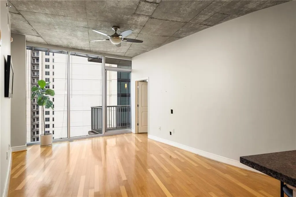 Unfurnished room featuring wood finished floors, ceiling fan, baseboards, and expansive windows