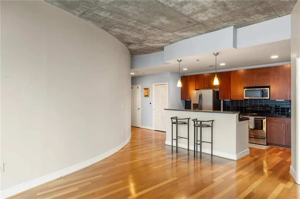 Kitchen featuring appliances with stainless steel finishes, dark countertops, a breakfast bar, light wood finished floors, and backsplash