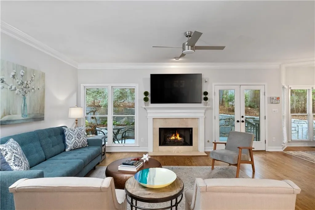 Living area featuring with hardwood floors, crown molding, healthy amount of natural light, a fireplace, and french doors