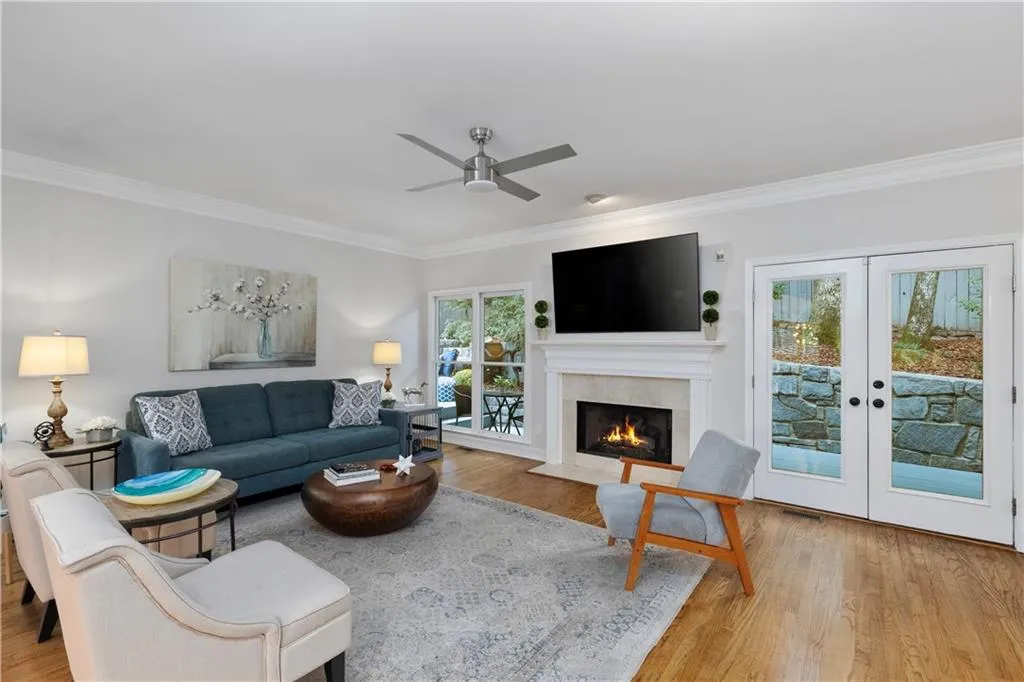 Living room featuring crown molding, hardwood flooring, french doors, a premium fireplace, and ceiling fan