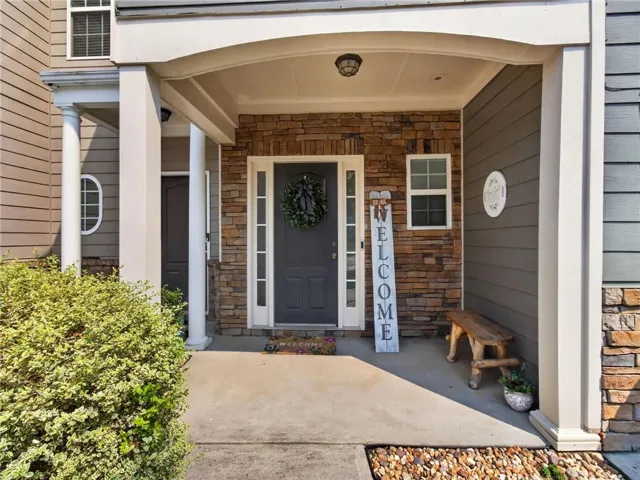 Covered front entry featuring stone veneer and horizontal siding