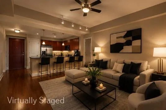 Open-concept living space featuring wood-finish flooring, a kitchen island with pendant lighting, stainless steel appliances, dark wood cabinetry, and a ceiling fan Evening View