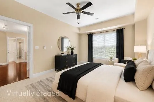 Large primary bedroom with neutral wall tones and neutral colored carpet, adjacent to custom closet system and bathroom.-Daylight View