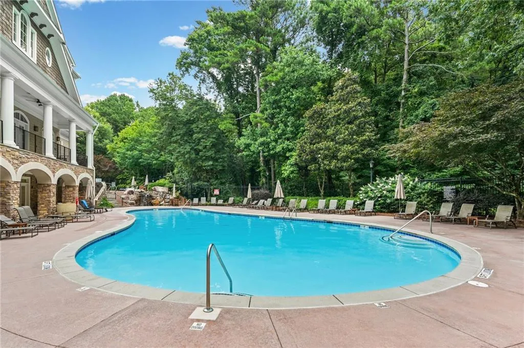 Resort-style pool area featuring a large freeform swimming pool with integrated steps, surrounded by a spacious concrete deck