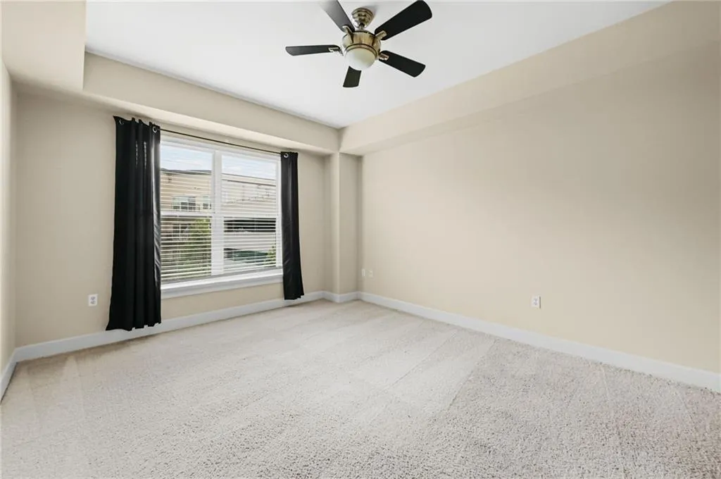 Large primary bedroom with neutral wall tones and neutral colored carpet, adjacent to custom closet system and bathroom.
