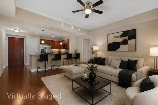 Open-concept living space featuring wood-finish flooring, a kitchen island with pendant lighting, stainless steel appliances, and track lighting