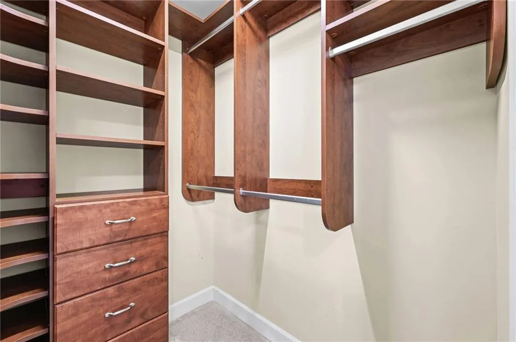 Built-in large custom closet system featuring wood-finish cabinetry, integrated shelving, and multiple hanging rods
