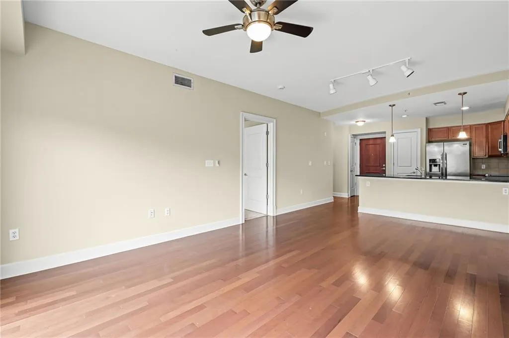 Spacious living area featuring wood-finish flooring, neutral paint, and access to a large balcony