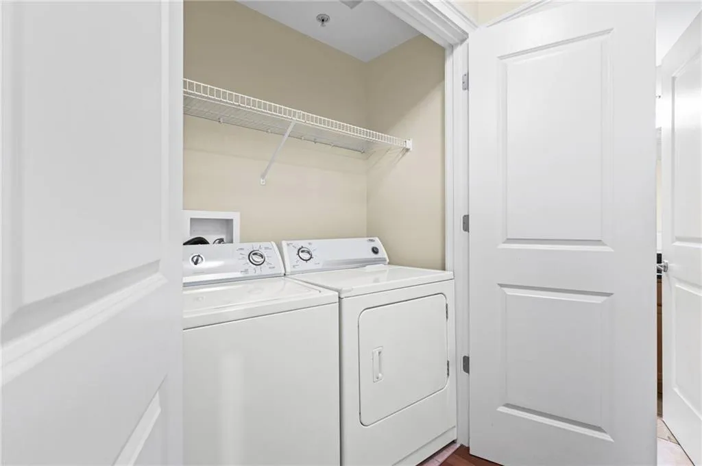 Dedicated laundry area featuring a white wire shelf, light-toned walls, and wood-finish flooring