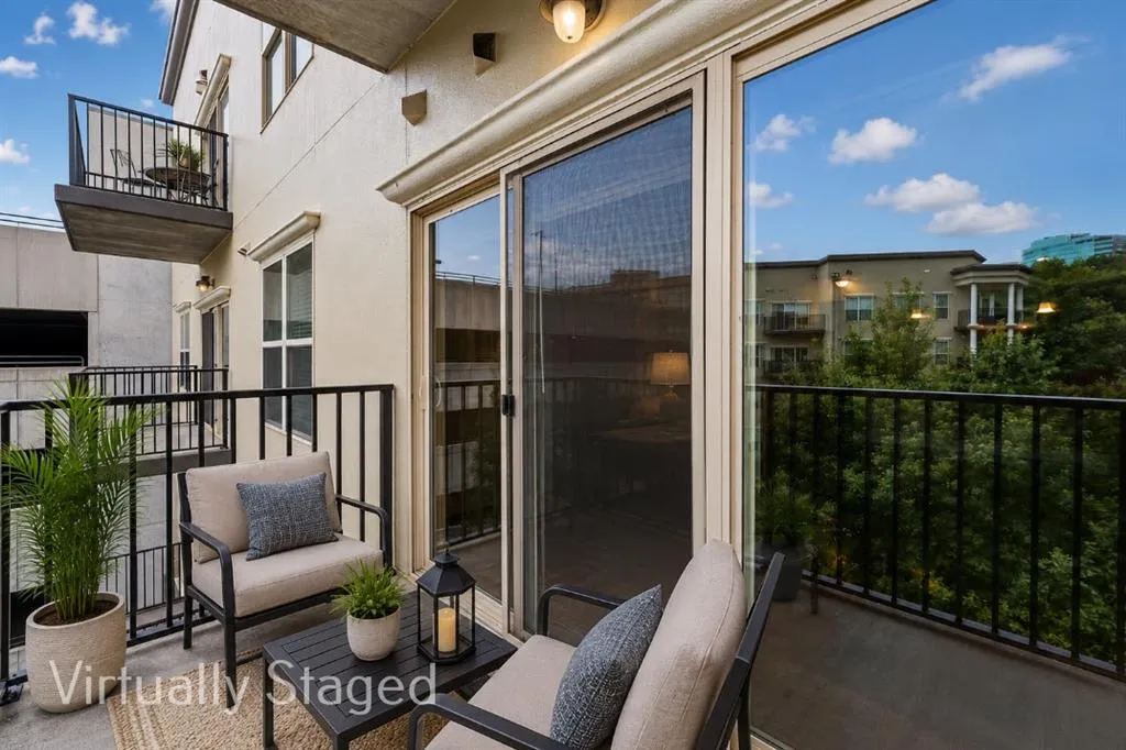 Private balcony featuring a sliding glass door entry, metal railings, and an exterior light fixture