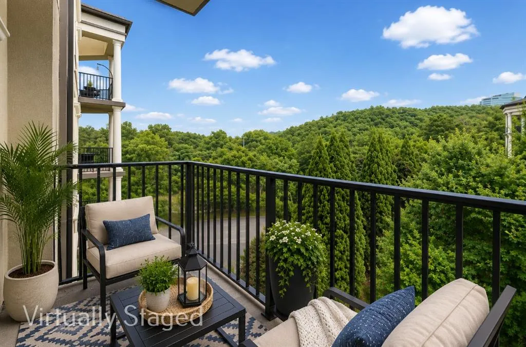 Spacious outdoor balcony with black metal railings, offering expansive tree-lined scenery