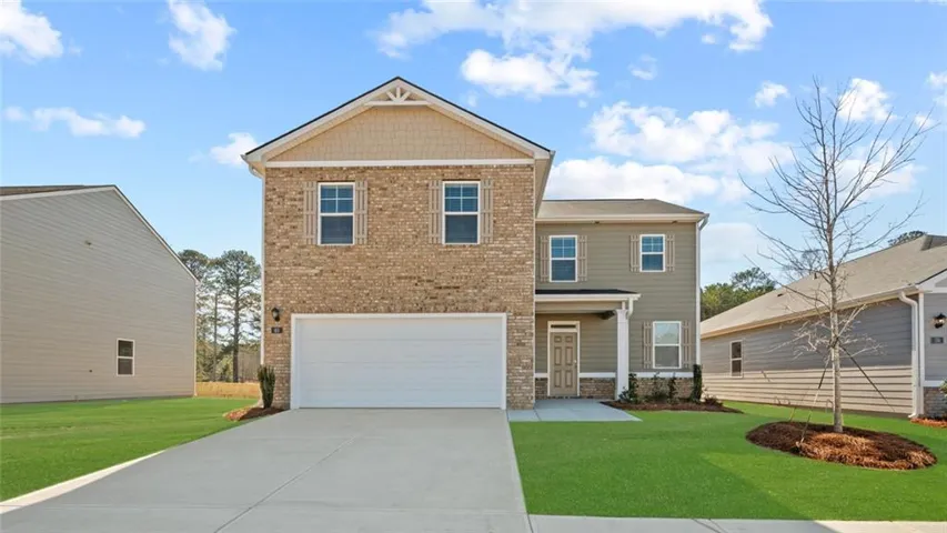 Two-story residence featuring a brick and siding facade, an attached front-facing garage, a concrete driveway, and a covered front porch with columns