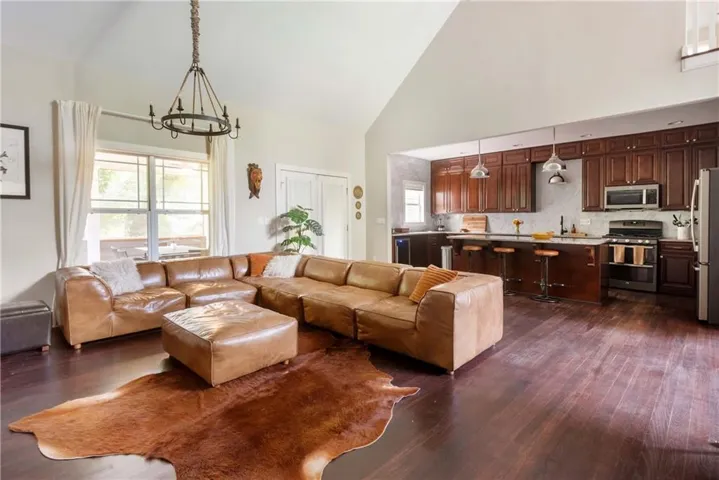 Open-concept living space featuring vaulted ceilings and dark wood-finish flooring