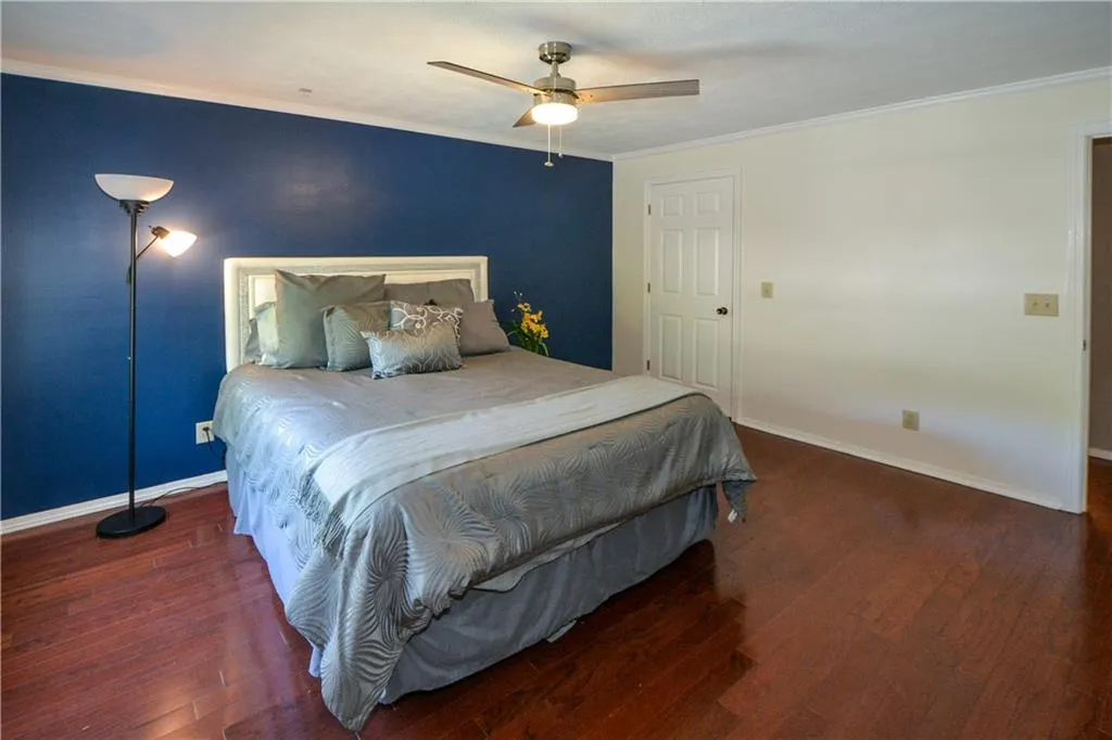 Bedroom with ornamental molding, dark wood-style flooring, and a ceiling fan
