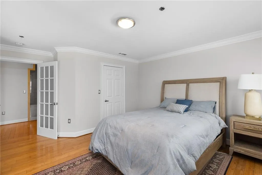 Hardwood flooring featuring a decorative area rug, crown molding, and light gray wall paint