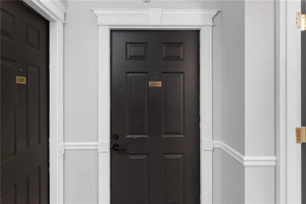 Black paneled door featuring decorative white trim and a matte black doorknob