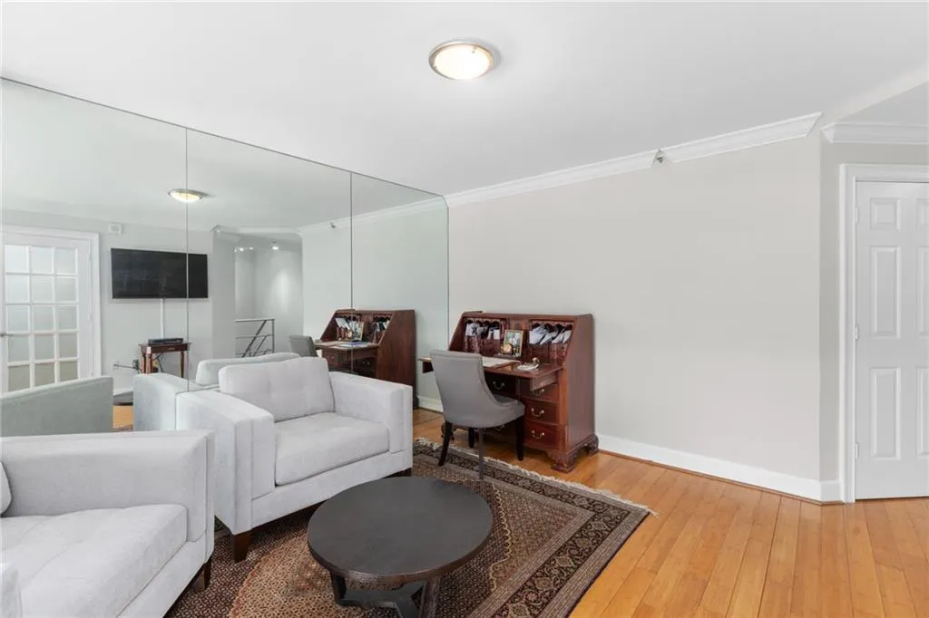 Hardwood flooring extends throughout this space featuring crown molding and a full-wall mirror installation