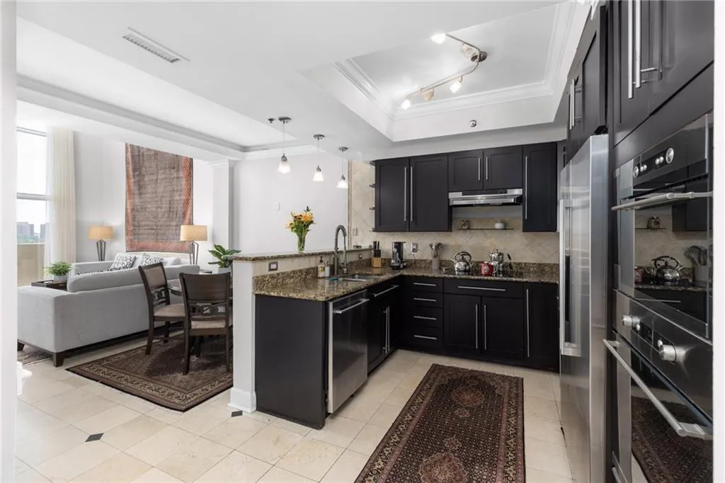 Open-concept living space featuring a kitchen with dark cabinetry, stainless steel appliances, granite countertops, and a stone backsplash