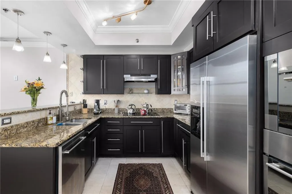 U-shaped kitchen featuring dark wood cabinetry, granite countertops, and stainless steel appliances