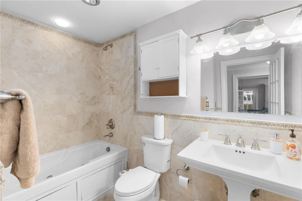 Bathroom featuring a pedestal sink, a bathtub with a shower combination, and a built-in medicine cabinet