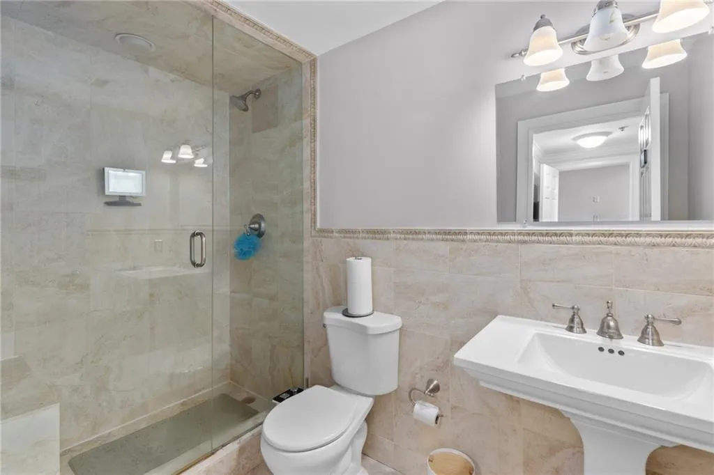 Pedestal sink with brushed nickel faucet, full-width vanity mirror, and three-light vanity fixture