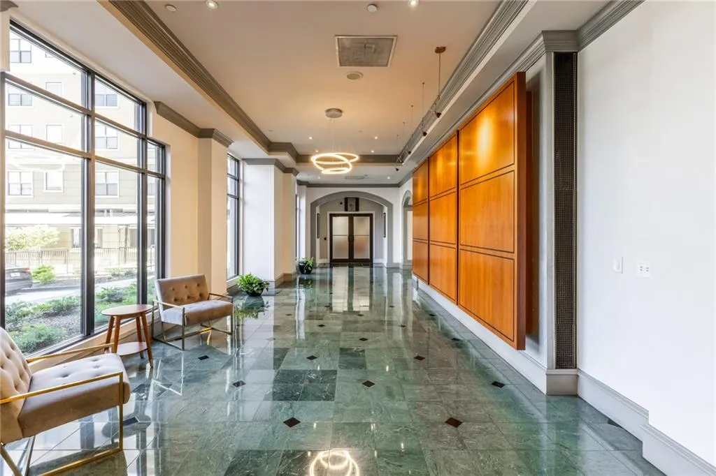 Hallway featuring expansive window walls, green stone tile flooring with dark accent squares, recessed lighting, and a large wood panel wall accent