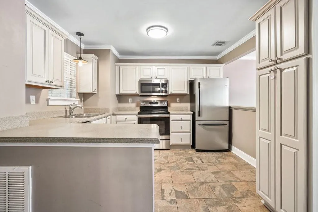 Kitchen with hanging light fixtures, light tile flooring, ornamental molding, stainless steel appliances, and sink